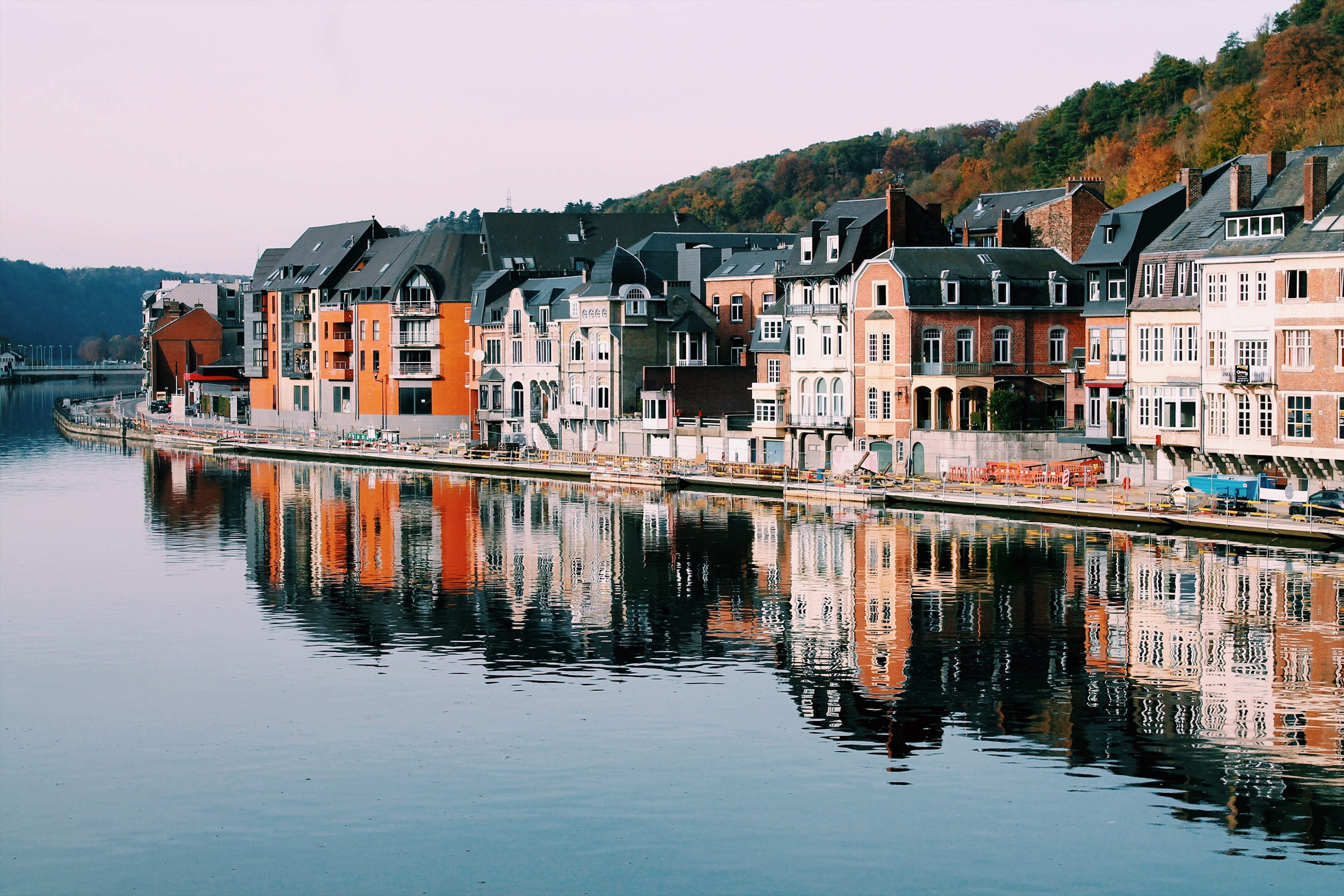 Buildings on a river in Belgium surrounded by trees.